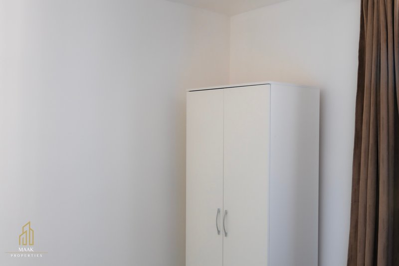 Bedroom corner with white wardrobe, brown curtains and plain walls