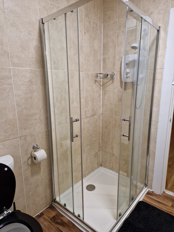 Bathroom with enclosed shower cubicle, tiled walls, and toilet visible