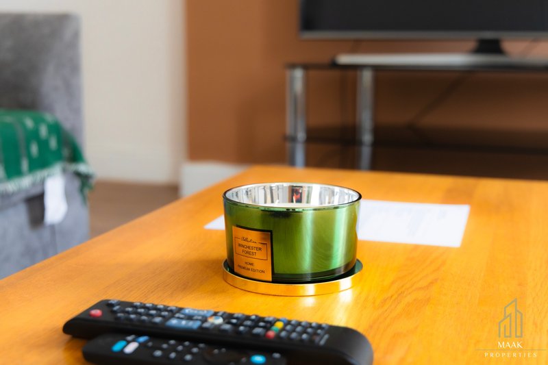 Orange wooden table with remote control, candle, and green plant in background