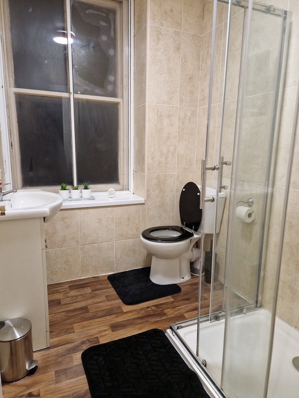 Modern bathroom with toilet, shower enclosure, window and wooden floor