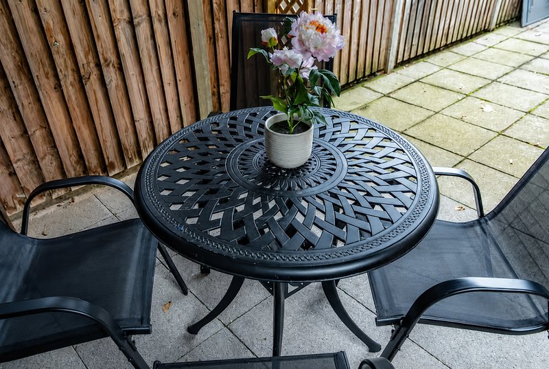 Patio garden table with potted flowering plant and two chairs