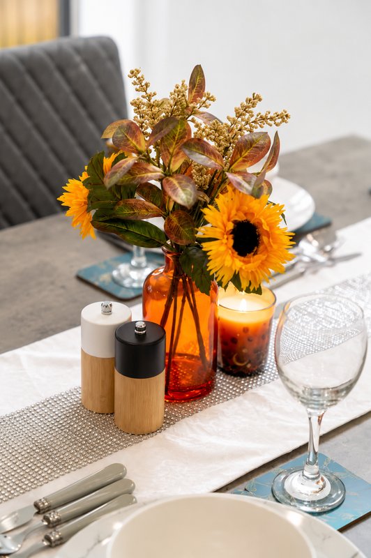 Dining table with place setting, flowers in amber vase, and table décor