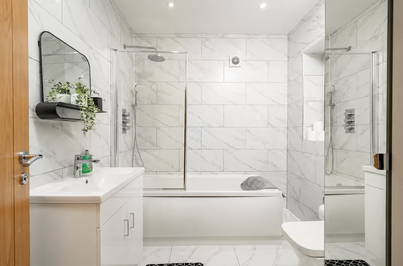 Modern bathroom with white marble tiles, walk-in shower, bathtub, and floating vanity with mirror