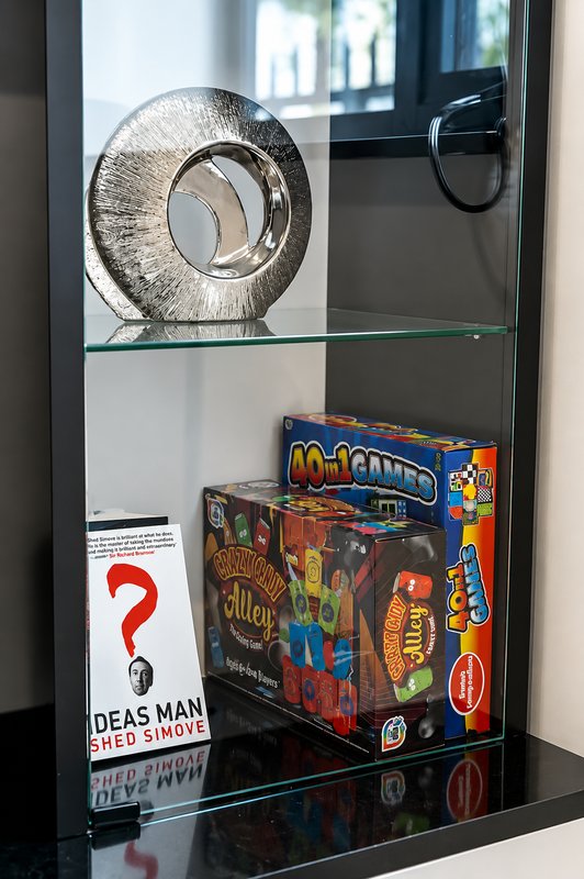 Glass display shelf with decorative metal sculpture, board games, and collectible items