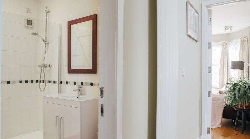 Modern bathroom with white vanity, mirror, shower enclosure and tiled walls