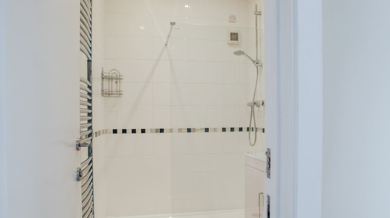 Modern bathroom shower enclosure with white tile walls and decorative border tile detail