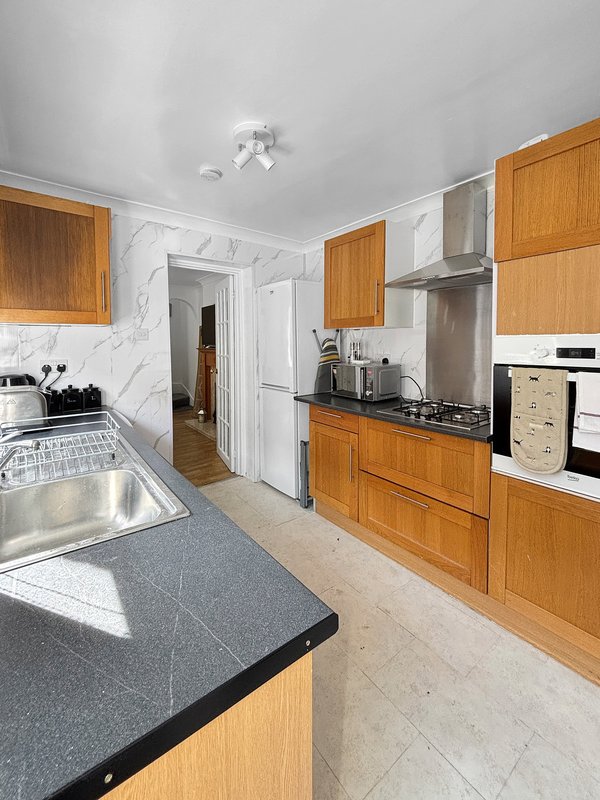 Modern kitchen with wooden cabinets, marble splashback, island countertop and stainless steel appliances
