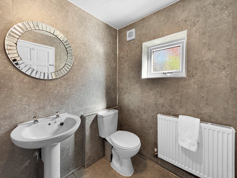 Bathroom with pedestal sink, toilet, radiator, mirror and small window