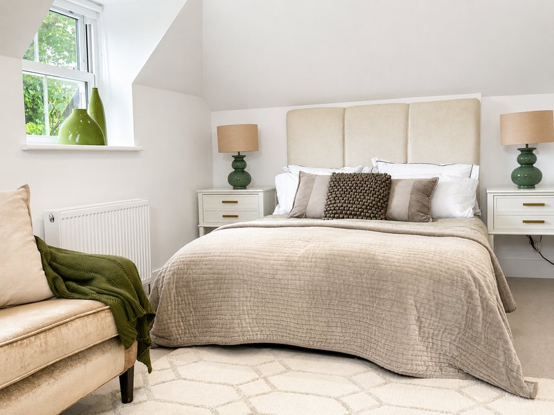 Bright modern bedroom with upholstered bed, cream bedding, matching nightstands