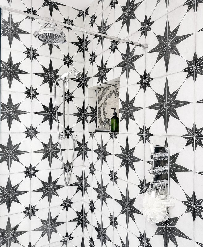 Bathroom wall with black and white star-pattern tiles, shelf with green bottle and toiletries