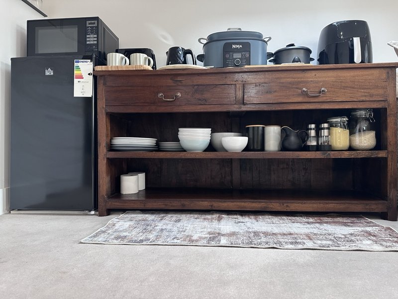 Kitchen counter with wooden shelving unit, appliances, and tableware display