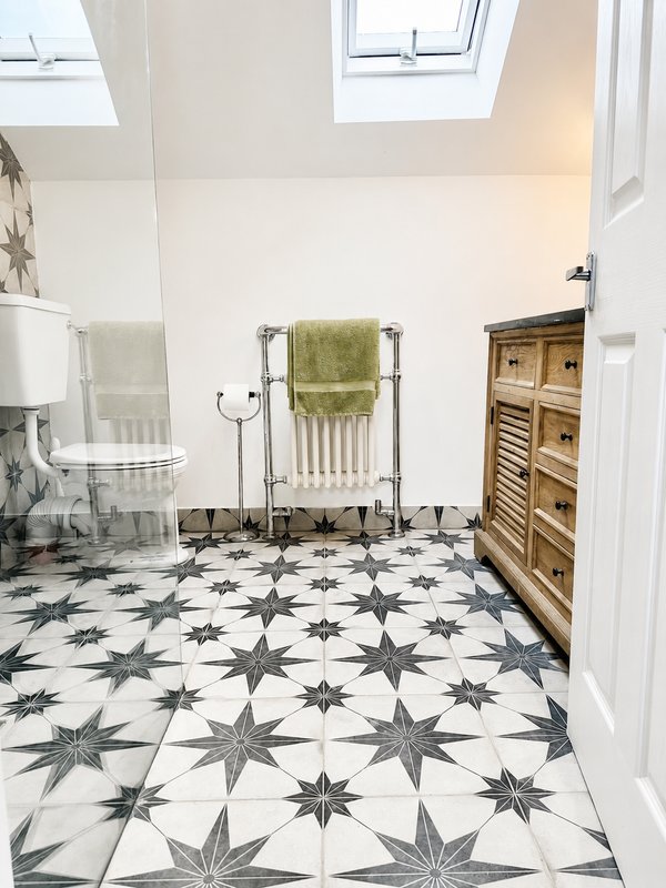 Modern bathroom with patterned floor tiles, towel rail, wooden storage cabinet and skylight