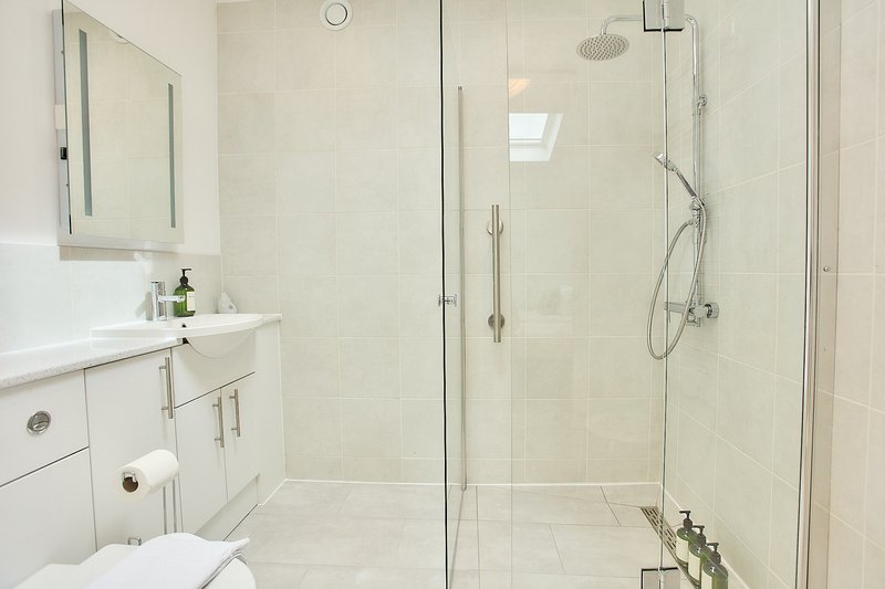 Modern bathroom with white vanity, mirror, toilet, and glass-enclosed shower