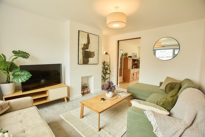 Modern living room with green sofa, wooden coffee table, TV unit and potted plants