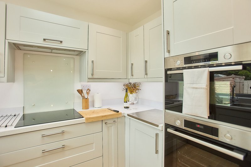 Modern white kitchen with integrated appliances, wooden worktop and induction hob