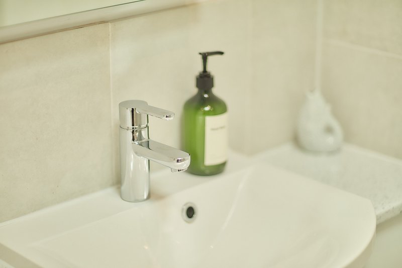 Bathroom sink with chrome faucet, green soap dispenser and white towel
