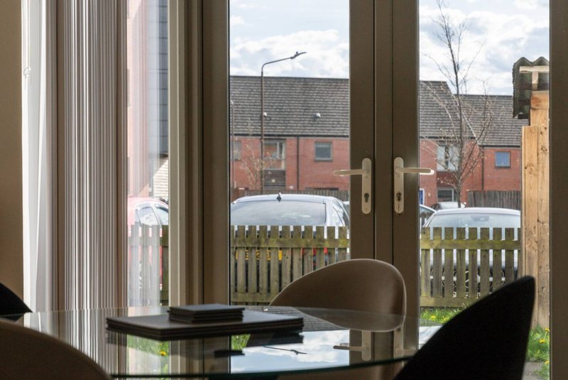 Modern interior with desk, chairs, and window overlooking garden and brick houses