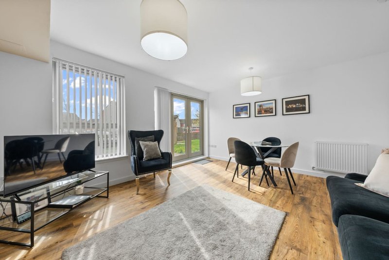 Bright living room with dining table, TV, comfortable seating and garden view