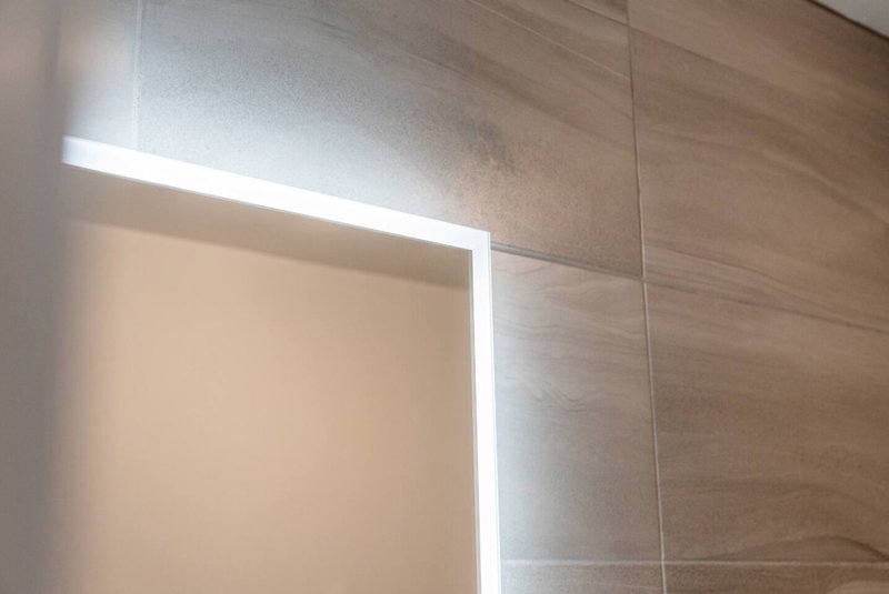 Modern bathroom with illuminated mirror and light wood tile wall