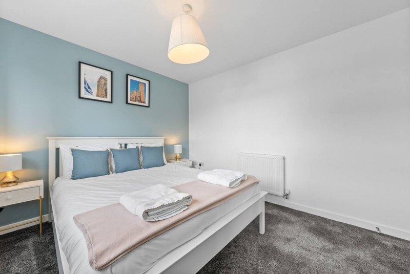 Modern bedroom with double bed, blue headboard wall, pendant light and bedside lamps