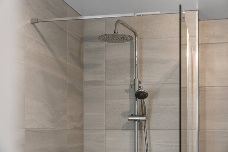 Modern bathroom shower enclosure with rainfall showerhead and handheld spray attachment