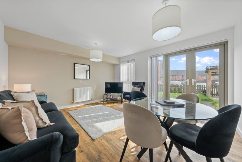 Modern open-plan living room with seating area, dining table, and glass doors overlooking city views