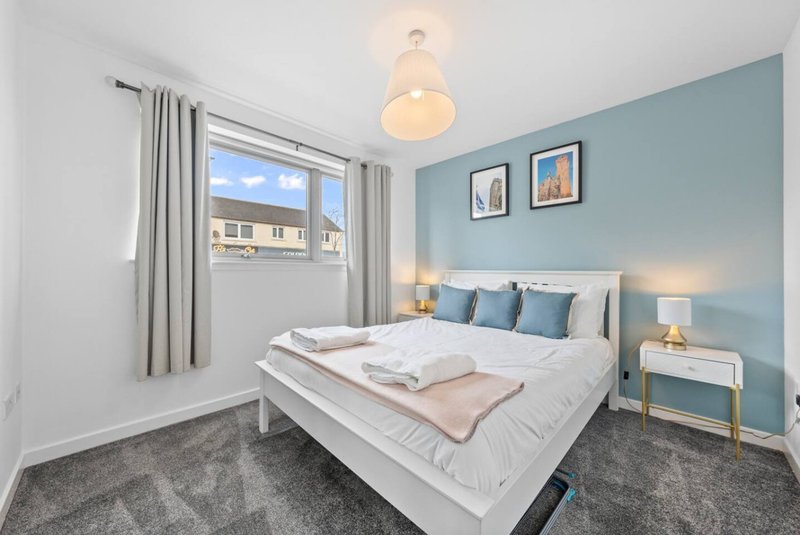 Modern bedroom with double bed, blue accent wall, pendant light and window with street view