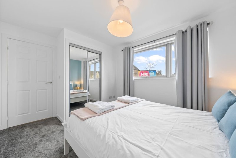 Bright bedroom with double bed, pendant light, grey curtains and ensuite access