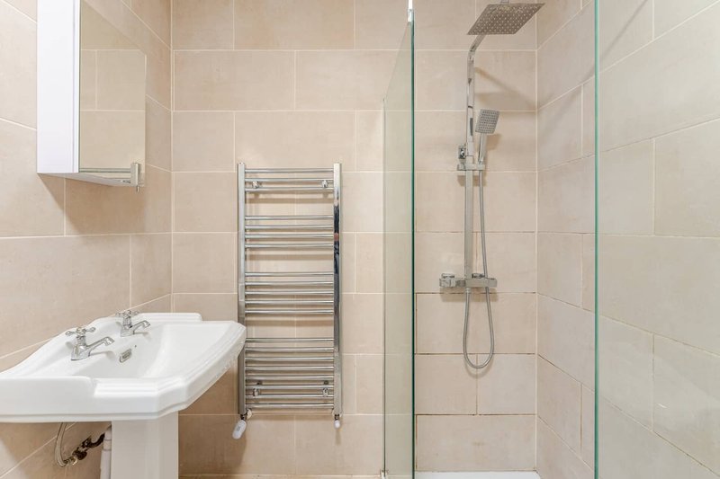 Modern bathroom with pedestal sink, heated towel rail, and glass-enclosed shower cubicle