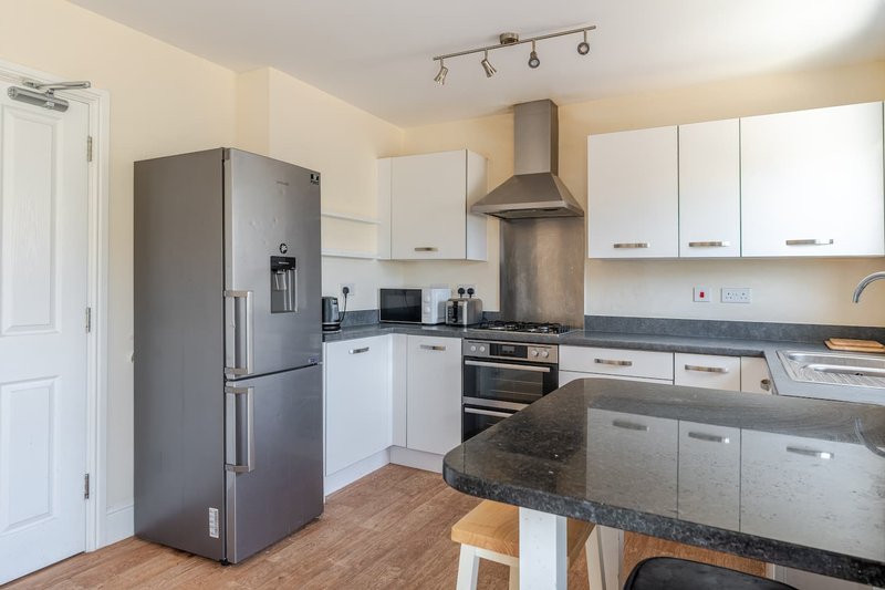 Modern kitchen with white cabinets, stainless steel appliances, dark countertops and island seating