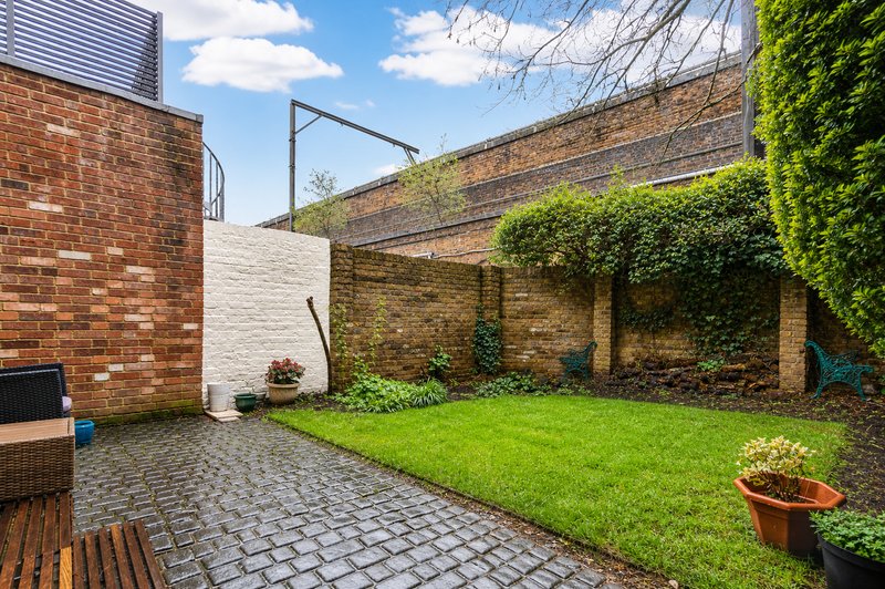 Contemporary brick courtyard with paved seating area, manicured lawn and ivy-covered walls