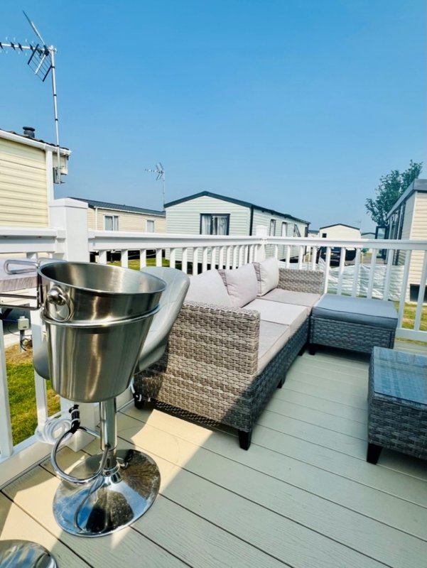 Decked outdoor seating area with cushioned furniture, metal heater, and railings overlooking residential street