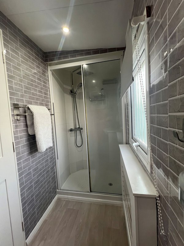 Modern bathroom with walk-in shower, grey subway tile walls, and vinyl flooring