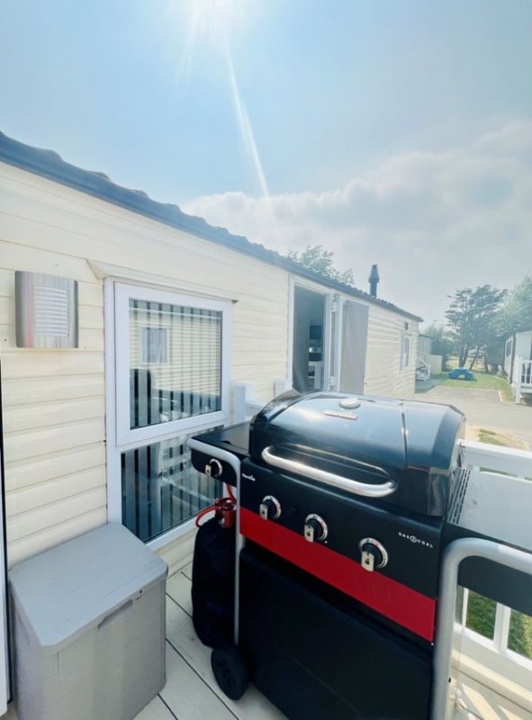 Exterior of mobile home with black and red barbecue grill on patio deck