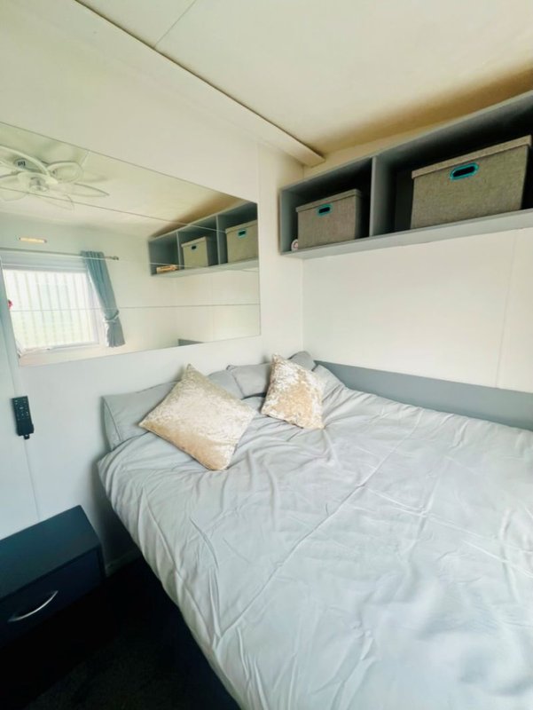 Compact bedroom with double bed, storage shelves, window and neutral décor