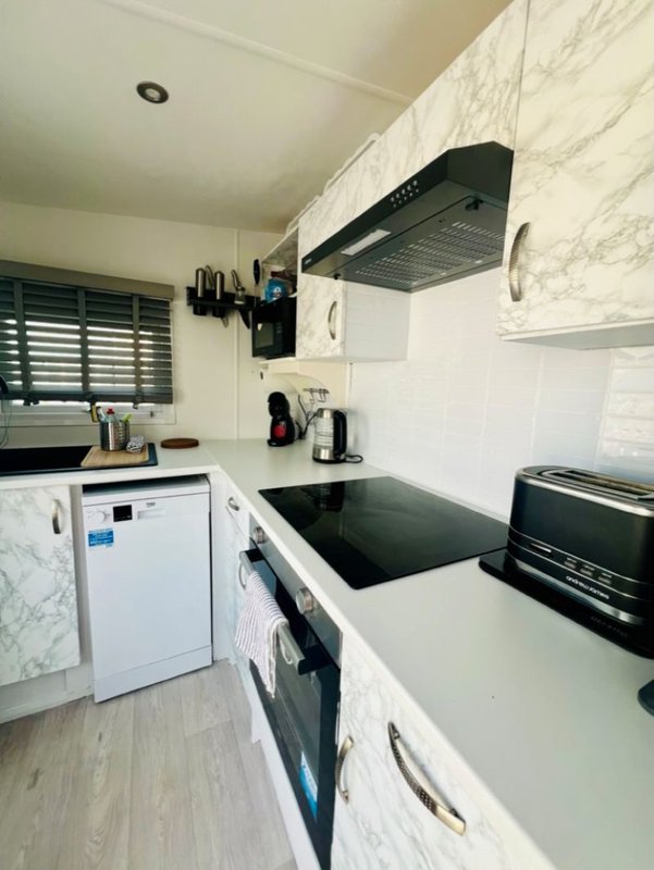 Modern kitchen with white cabinetry, marble countertops, black stovetop and extractor hood