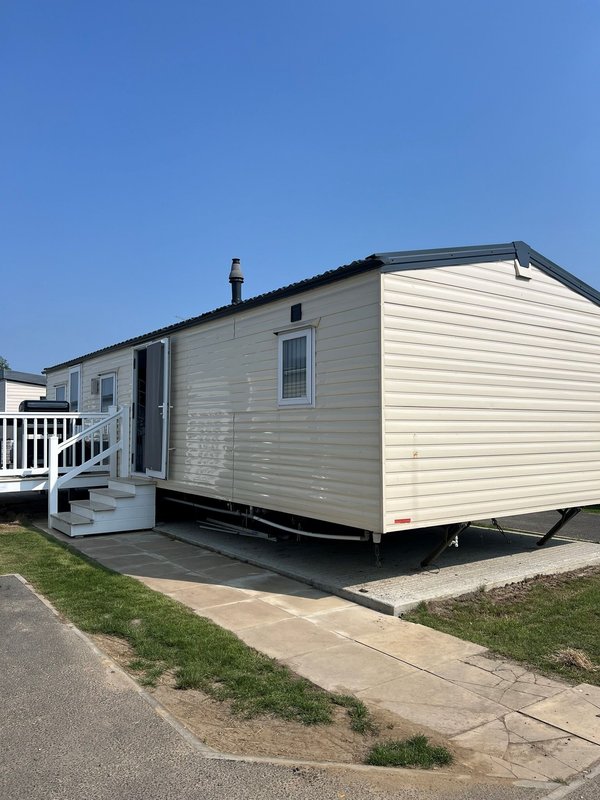Mobile home exterior with cream siding, white deck, entrance door and windows