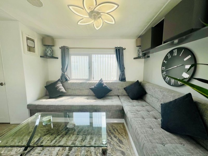 Living room with grey L-shaped sofa, black cushions, window seat, and modern ceiling light