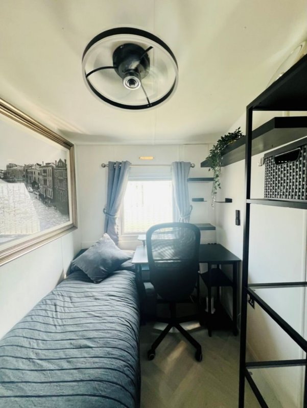 Compact bedroom with single bed, desk chair, ceiling fan and loft bed frame