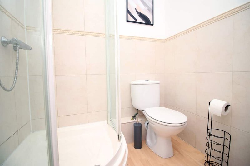 Clean bathroom with toilet, shower enclosure, wooden flooring and wall art