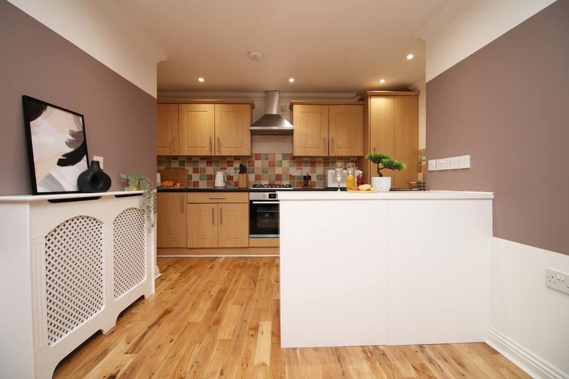 Modern kitchen with wooden cabinets, tiled backsplash, white counters and wooden flooring
