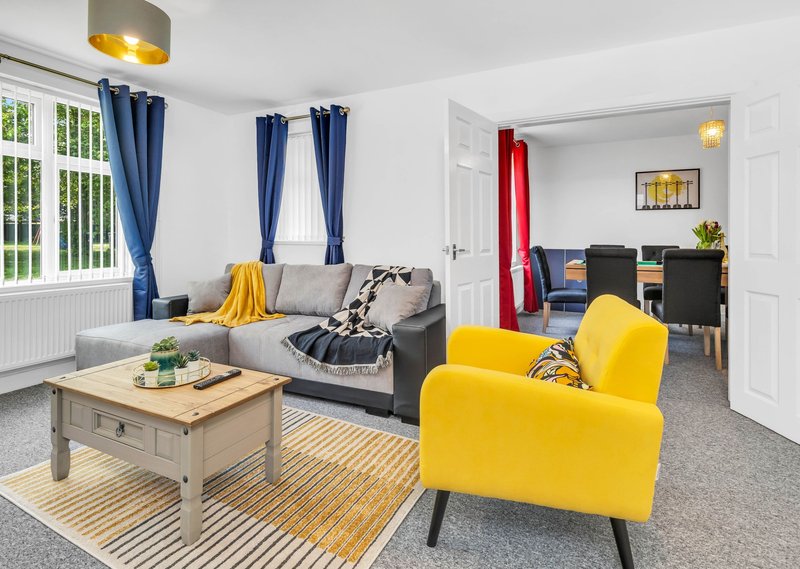 Open-plan living room with gray sofa, yellow armchair, wooden coffee table and blue curtains