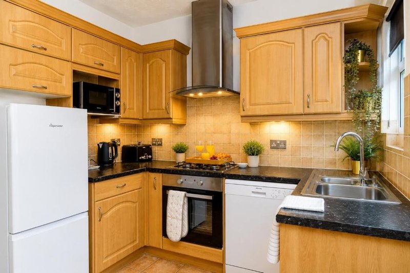 Bright modern kitchen with wooden cabinets, stainless steel appliances and black countertops