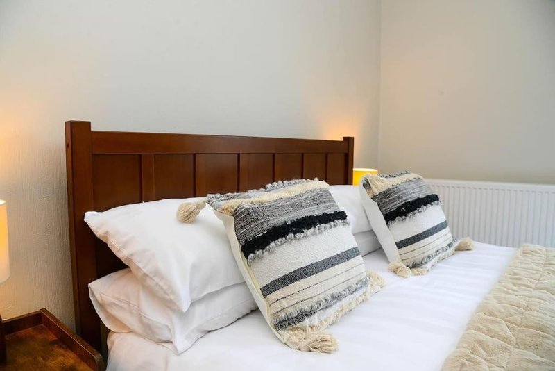 Bedroom with wooden headboard, white pillows, striped bedding and warm lighting