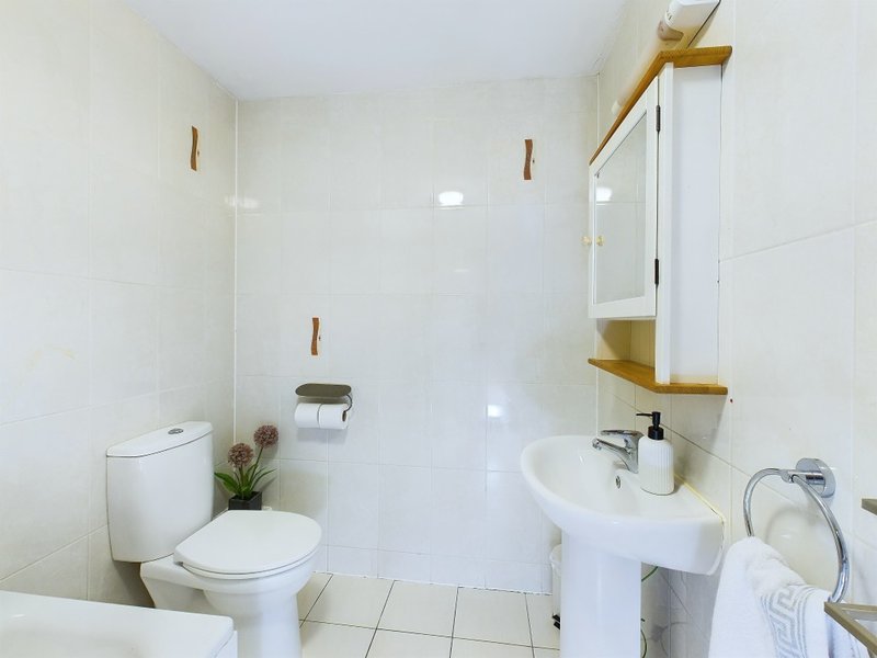 Modern bathroom with toilet, sink, shower enclosure, and brass fixtures