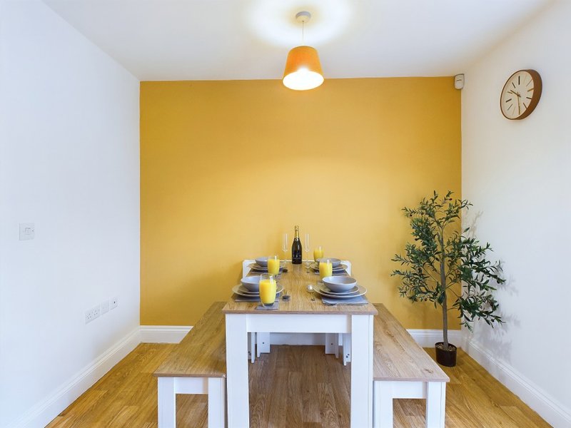 Dining nook with white table, benches, place settings, and yellow accent wall