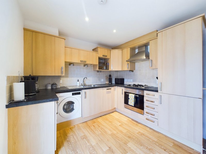 Modern kitchen with wooden cabinets, white appliances, black countertops and wooden flooring