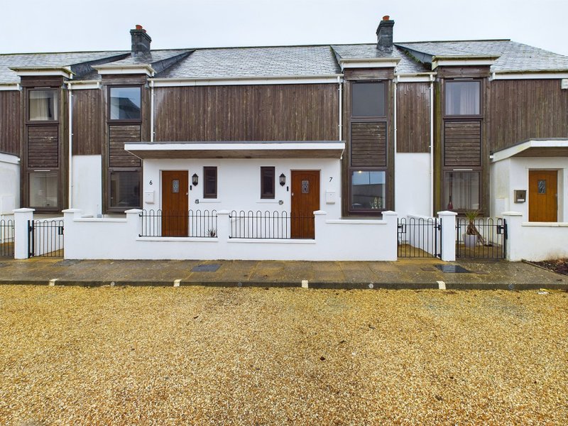 Terraced townhouses with white trim, brown wooden cladding, gravel forecourt and front porches
