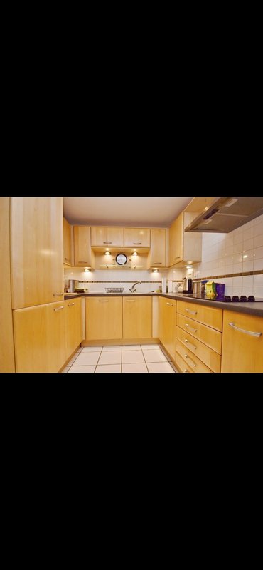 Galley kitchen with wooden cabinets, white countertops, and stainless steel appliances