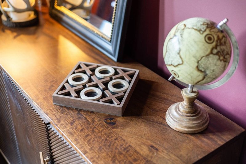 Wooden desk with decorative globe, tic-tac-toe game, and framed artwork